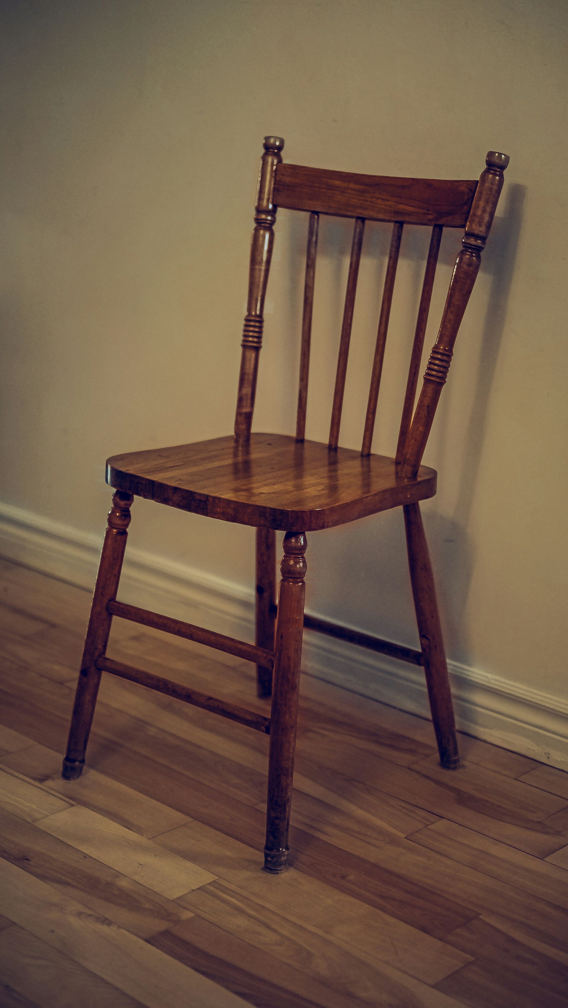 A wooden chair sitting on top of a hard wood floor